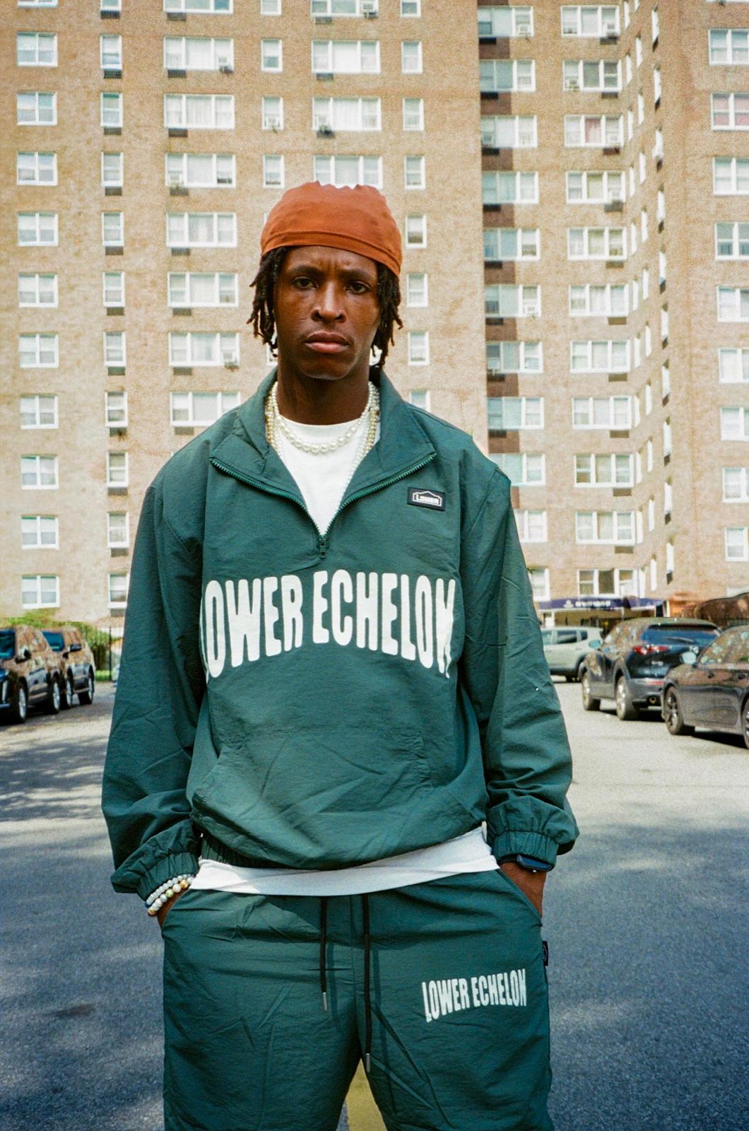 Model in a green Run It Up tracksuit in front of NYC housing towers